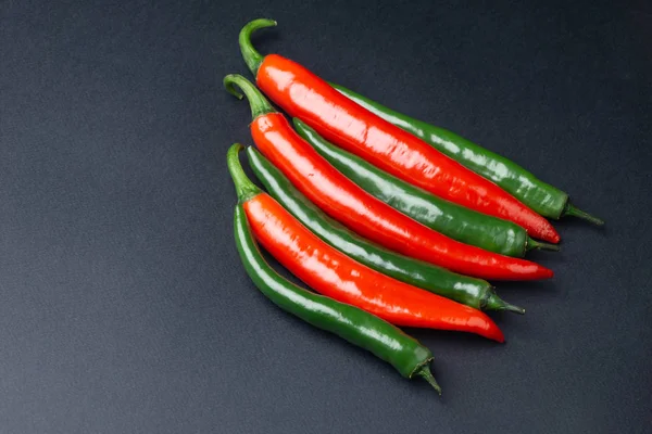 Pimientos chile verde y rojo sobre fondo negro vista superior. Comida picante caliente . —  Fotos de Stock