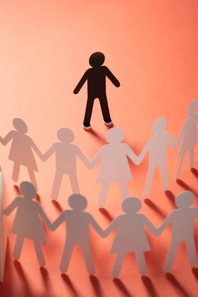 Papper mänsklig figur stående framför papper människor höll händerna på röd yta. Bulling, segregation, konflikten koncept. — Stockfoto