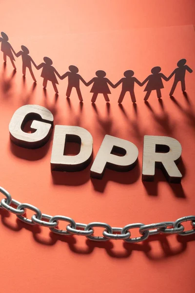 GDPR letters in front of human paper figures and metal chain. General data protection concept.