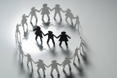 Üç insan kağıt rakamlar beyaz yüzey üzerinde el ele tutuşarak kağıt insanların daire çevrili. Bulling, segregasyon, çatışma kavramı.
