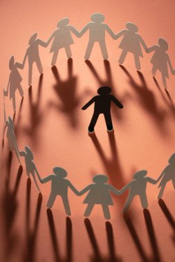 Kağıt insan figürü kırmızı yüzey üzerinde el ele tutuşarak kağıt insanların daire çevrili. Bulling, segregasyon, çatışma kavramı.