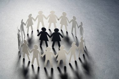 Kağıt şekil kadın çift gri yüzey üzerinde el ele tutuşarak kağıt insanların daire çevrili. Bulling, azınlıklar, çatışma kavramı.