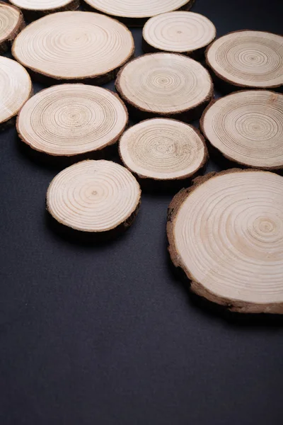 在平面黑色表面上有一年生年轮的松树横截面。木材片特写. — 图库照片