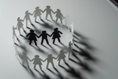 Üç insan kağıt rakamlar beyaz yüzey üzerinde el ele tutuşarak kağıt insanların daire çevrili. Bulling, segregasyon, çatışma kavramı.
