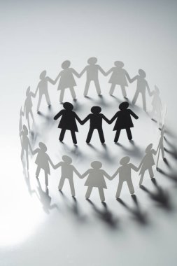 Üç insan kağıt rakamlar beyaz yüzey üzerinde el ele tutuşarak kağıt insanların daire çevrili. Bulling, segregasyon, çatışma kavramı.
