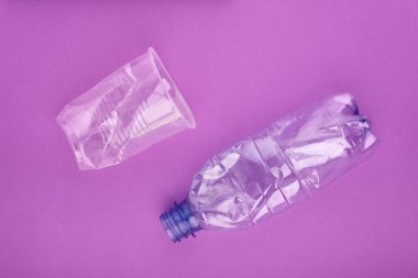 Mor arka planda plastik şişe ve bardak çöktü. Plastik kullanım konsepti. Ekolojik sorun, küresel çevre.
