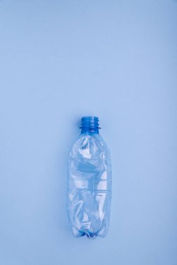 Parlak mavi arka planda plastik şişe çöktü. Plastik kullanım konsepti. Ekolojik sorun, küresel çevre.