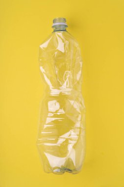 Sarı arka planda plastik şişe çöktü. Plastik kullanım konsepti. Ekolojik sorun, küresel çevre.