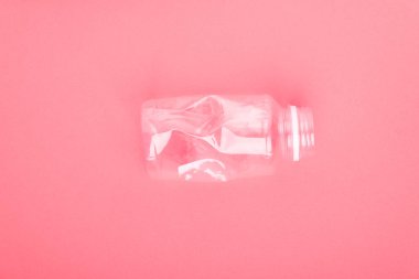 Mercan pembe arka planda plastik şişe çöktü. Plastik kullanım konsepti. Ekolojik sorun, küresel çevre.