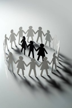 Üç insan kağıt rakamlar beyaz yüzey üzerinde el ele tutuşarak kağıt insanların daire çevrili. Bulling, segregasyon, çatışma kavramı.