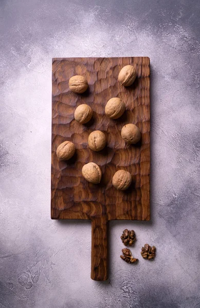 Nueces enteras sobre tabla tallada de madera, vista superior. Composición saludable de frutos secos y semillas . — Foto de Stock