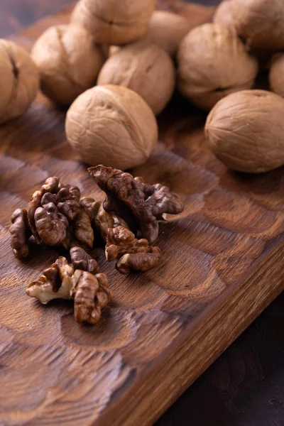 Bunch of walnuts on carved wooden board. Healthy nuts and seeds composition, background. — Stock Photo, Image