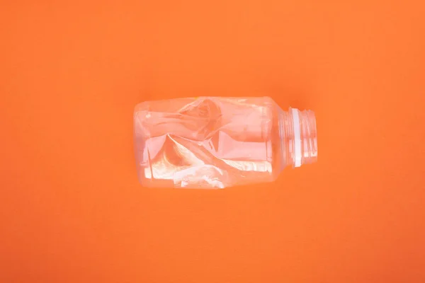 Розбита пластикова пляшка на помаранчевому фоні. Концепція використання пластику. Екологічна проблема, глобальне середовище . — стокове фото
