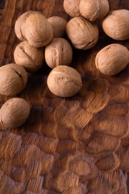 Oyma ahşap tahta üzerinde yatan tüm ceviz bir grup. Sağlıklı fındık ve tohum kompozisyon, arka plan.
