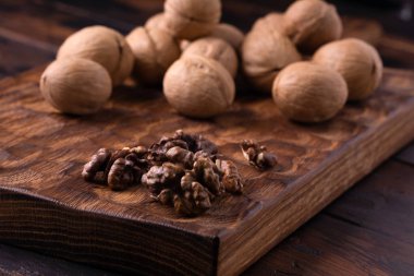 Oyulmuş tahta üzerine bir demet ceviz. Sağlıklı fındık ve tohum bileşimi, arka plan.