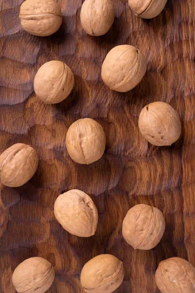 Bunch of whole walnuts lying on carved wooden board. Healthy nuts and seeds composition, background. — Stock Photo, Image