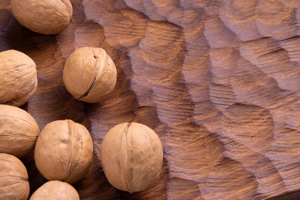 Кучка грецких орехов лежит на резной деревянной доске. Здоровый состав орехов и семян, фон . — стоковое фото