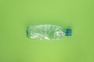 Yeşil arka planda plastik şişe çöktü. Plastik kullanım konsepti. Ekolojik sorun, küresel çevre.