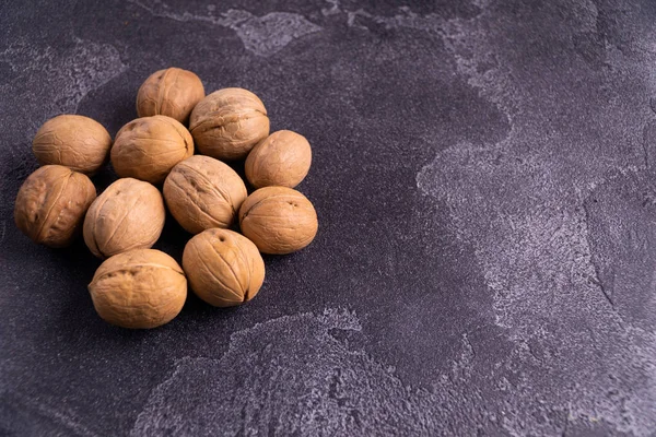 Manojo de nueces enteras en la superficie de pizarra azul oscuro. Composición saludable de la dieta . —  Fotos de Stock