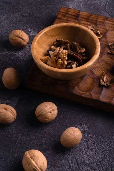 Nueces en cuenco de madera y sobre tabla de pizarra azul. Composición saludable de frutos secos y semillas . —  Fotos de Stock