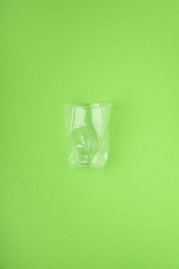 Yeşil arka plan üzerinde çöktü plastik bardak. Plastik kullanım konsepti. Ekolojik sorun, küresel çevre.