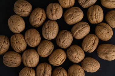 Ceviz siyah yüzey, üst görünümü üzerinde kabuk içinde. Yuvarlak ceviz arka plan. Sağlıklı fındık ve tohum arka plan.