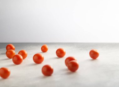 Kiraz domates beyaz taş beton masa üzerinde dağınık, kopya alanı ile. Yemek pişirmek için malzemeler.