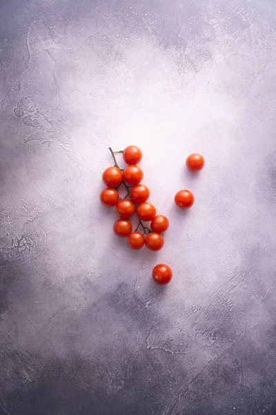 Ένα μάτσο ντοματίνια σε τσιμεντένιο τραπέζι με λευκές πέτρες, κορυφαία θέα με χώρο αντιγραφής. Συστατικά για το μαγείρεμα. — Φωτογραφία Αρχείου