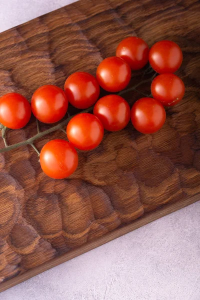 Verse tomaten op gesneden houten snijplank en helder getextureerde oppervlak. — Stockfoto