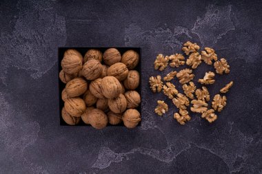 Mavi desenli yüzeyde, kare bir tabakta tam ve kırılmış cevizler, üst manzara. Sağlıklı fındık ve tohum bileşimi.