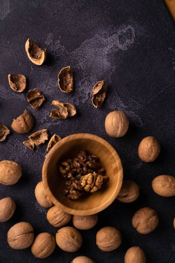 Ahşap kase ve siyah kayrak yüzeyinde ceviz. Sağlıklı fındık ve tohum bileşimi.