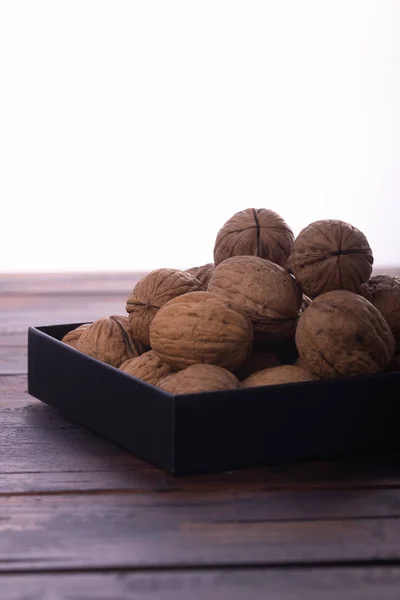 Nueces enteras sobre mesa de madera, vista lateral sobre fondo blanco. Composición saludable de frutos secos y semillas . —  Fotos de Stock