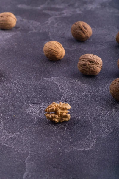 Nueces enteras y agrietadas en superficie de textura azul, vista lateral. Composición saludable de frutos secos y semillas . — Foto de Stock