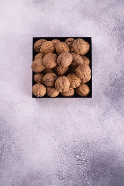 Nueces en una placa cuadrada sobre una superficie de textura brillante, vista superior. Composición saludable de frutos secos y semillas . —  Fotos de Stock