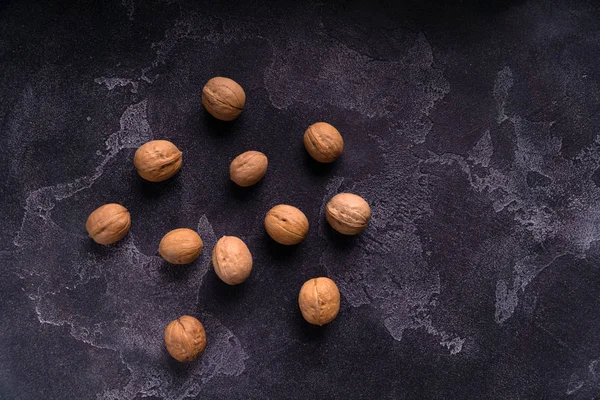 Manojo de nueces enteras sobre fondo de pizarra azul oscuro. Composición saludable de la dieta . —  Fotos de Stock