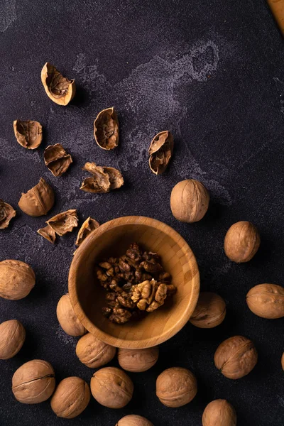 Nueces en cuenco de madera y en la superficie de pizarra negra. Composición saludable de frutos secos y semillas . —  Fotos de Stock