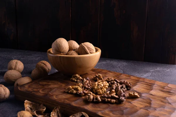 Nueces en cuenco de madera sobre tabla tallada en madera. Composición saludable de frutos secos y semillas . —  Fotos de Stock