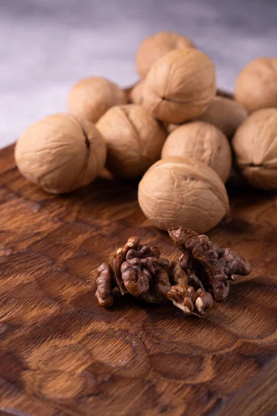 Bunch of whole walnuts on carved wooden board. Healthy nuts and seeds composition, background. — Stock Photo, Image