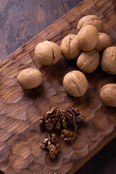 Ramo de nueces sobre tabla de madera tallada. Composición saludable de frutos secos y semillas, fondo . — Foto de Stock