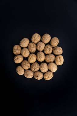 Ceviz kabuğunun ortasında siyah yüzey, üst görünümü. Yuvarlak ceviz arka plan. Sağlıklı fındık ve tohum bileşimi.