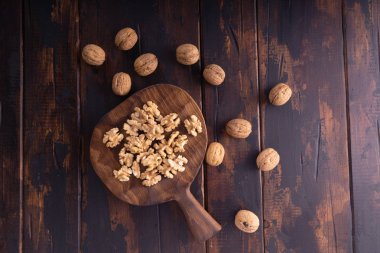 Kesme tahtası ve ahşap masa üzerinde kırık ve bütün ceviz, üst görünümü. Sağlıklı fındık ve tohum bileşimi.