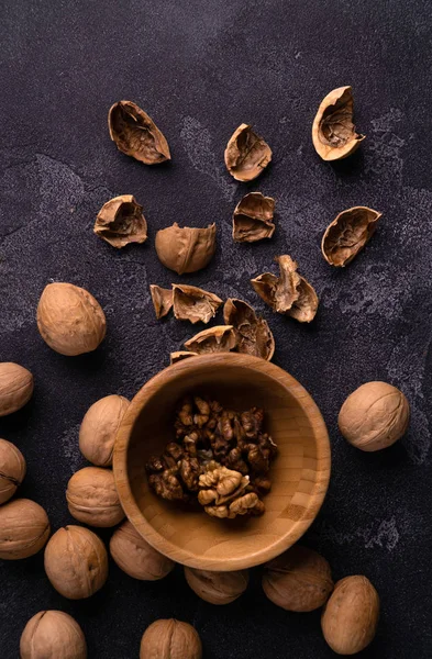Walnuts in wooden bowl and on black slate surface. Healthy nuts and seeds composition. — Stock Photo, Image