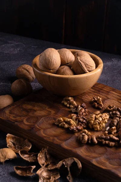Nueces en cuenco de madera sobre tabla tallada en madera. Composición saludable de frutos secos y semillas . —  Fotos de Stock
