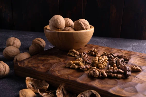 Nueces en cuenco de madera sobre tabla tallada en madera. Composición saludable de frutos secos y semillas . —  Fotos de Stock