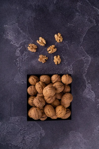 Nueces enteras y agrietadas en una placa cuadrada sobre una superficie de textura azul, vista superior. Composición saludable de frutos secos y semillas . —  Fotos de Stock