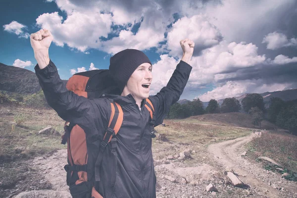 Ung vandrare skriker ut på toppen med händerna upphöjda, sidovy. — Stockfoto