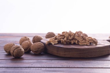 Kesme tahtası ve ahşap masa üzerinde kırık ve bütün ceviz, beyaz arka plan üzerinde yan görünüm. Sağlıklı fındık ve tohum bileşimi.