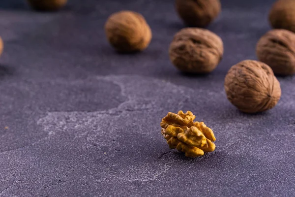 Nueces enteras y agrietadas en superficie de textura azul, vista lateral. Composición saludable de frutos secos y semillas . —  Fotos de Stock