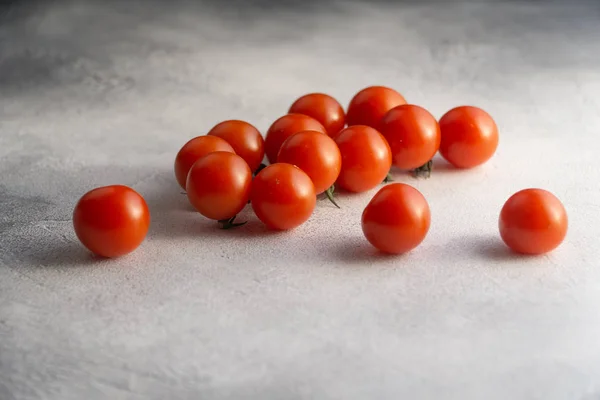 Bukiet pomidorków wiśniowych na białym betonowym stole, widok z boku z kopią przestrzeni. Składniki do gotowania. — Zdjęcie stockowe
