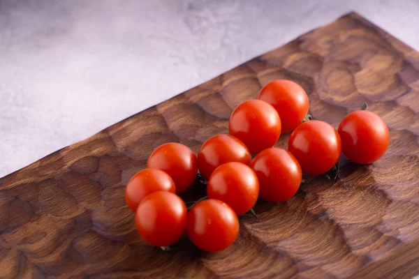 Tomates frescos en tabla de cortar de madera tallada y superficie texturizada brillante . — Foto de Stock